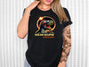 a woman wearing a black t - shirt with an image of a dinosaur on it