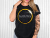 a woman wearing a black t - shirt with a solar eclipse on it