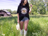 a woman in short shorts and cowboy boots standing in a field